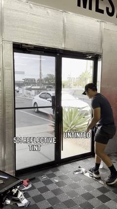 Installer applying 5% reflective commercial window film to a storefront glass door, with an untinted door beside it for comparison