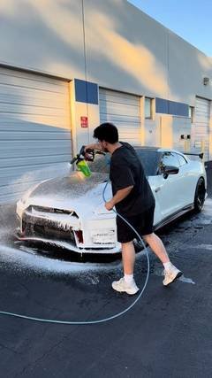 Technician foam washing a white sports car outside the Phantom Tint shop during a detail