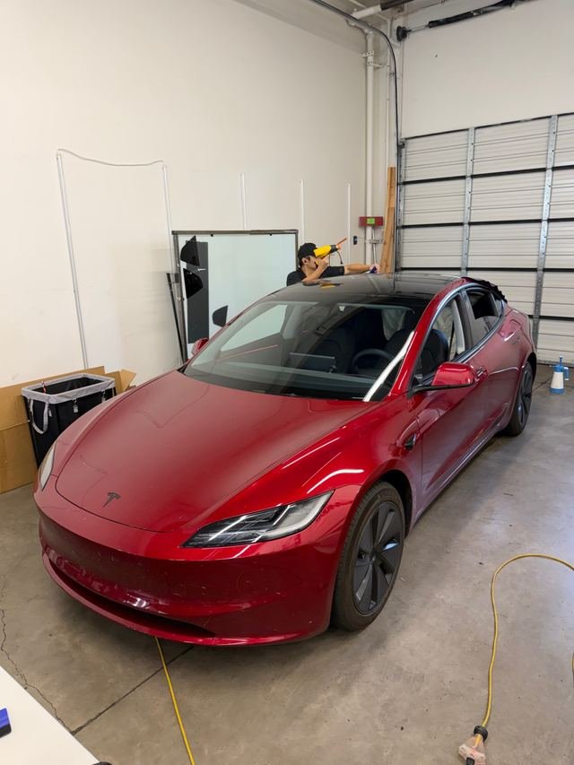 Red Tesla Model 3 during window tint installation
